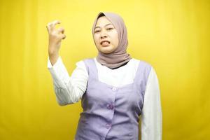 Beautiful young asian muslim woman upset, angry, dissatisfied, displeased, hateful, looking at camera isolated on yellow background photo