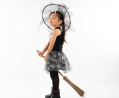 Retrato de niña asiática vistiendo de bruja linda para disfraz de halloween con escoba.