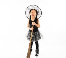 Portrait Asian little girl dressing in cute witch for Halloween costume with broom and isolated background. photo