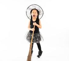 Retrato de niña asiática vestirse con linda bruja para disfraz de halloween con escoba y fondo aislado foto