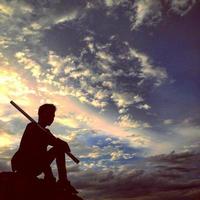 silhouette of a man sitting against an orange sky background. photo