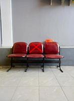 Close-up of empty waiting chairs with social distancing Red chairs with a cross symbol on chairs in office during Covid-19 or Coronavirus pandemic. photo