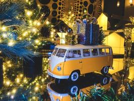 composición navideña. Autobús de juguete amarillo con regalos y el árbol de navidad en el fondo foto