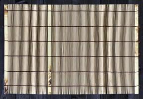 Bamboo mat on wooden table, top view photo