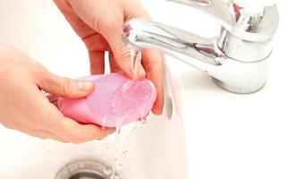 cepillo limpiador facial sónico bajo el agua en el baño, tratamiento casero para el cuidado de la piel foto
