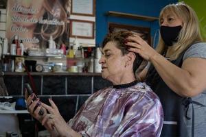 Latin hairdresser salon. Client checking her cell phone. photo