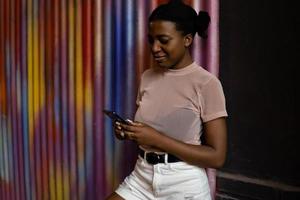 Happy black woman using smart phone and smiling. photo