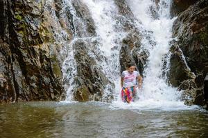 chica viajando cascada de vacaciones. la niña que disfruta jugando felizmente en la cascada. viajar por la naturaleza, viajar relajarse, viajar a tailandia. cascada de huai toh en krabi. foto