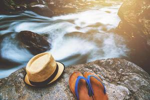 travel nature, Travel relax,Hat with sandals placed on rocks at the waterfall. photo