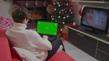 Man working with chroma key isolated laptop dispaly in a Christmas themed room. video