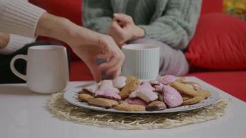 le coppie bevono il tè con i biscotti in una stanza a tema natalizio. video