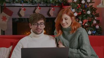 Couple celebrating Christmas with their friends using a video call.