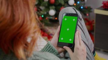 Woman holding smartphone with green screen Chroma Key Christmas background. video