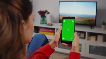 Green screen template smartphone in female hands at home.