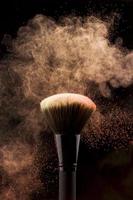 pincel de maquillaje con salpicaduras de polvo de color melocotón foto