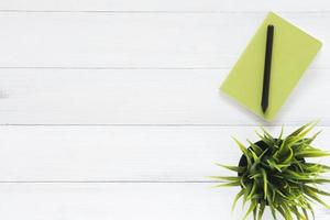 espacio de trabajo mínimo: foto creativa plana del escritorio del espacio de trabajo. Escritorio de oficina blanco Fondo de mesa de madera con cuadernos y bolígrafos y planta. vista superior con espacio de copia, fotografía plana.