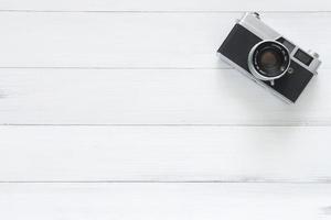 Minimal work space - Creative flat lay photo of workspace desk. Office desk wooden table with old camera. Top view with copy space. Top view of old camera over wooden table. Retro vintage filter.