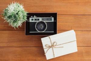 Christmas and New Year holidays gift box wrapped with white paper and ribbon bow on wood table - top view on wooden table top background. photo