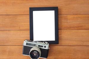 Creative flat lay photo of workspace desk. Office desk wooden table with old camera and poster mockup template. Top view with copy space. Top view of old camera over wooden table. Retro vintage filter