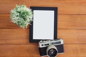 Creative flat lay photo of workspace desk. Office desk wooden table with old camera and poster mockup template. Top view with copy space. Top view of old camera over wooden table. Retro vintage filter