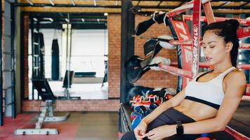 Young Asia lady kickboxing exercise workout feels tired after sport training on boxing ring in gym fitness class. Sportswoman recreational activity, functional training, healthy lifestyle concept. photo