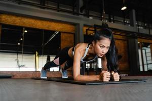 Happy young Asia lady exercise doing plank fat burning workout in fitness class. Athlete with six pack, Sportswoman recreational activity, functional training, healthy lifestyle concept. photo