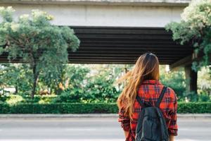 Young Asian women standing along the street enjoying her city lifestyle in a morning of a weekend waiting for outdoor activity. Young woman and her city lifestyle. city lifestyle and outdoor concept. photo