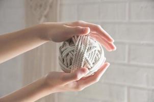 Ball of yarn for knitting macrame lies on the hand photo