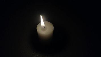 brennende Kerze auf schwarzem Hintergrund. die Kerzenflamme flackert langsam. video