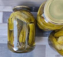 Pickled cucumbers in a glass jar. Three large jars of pickles on the table. Preparing food and snacks for the winter. photo