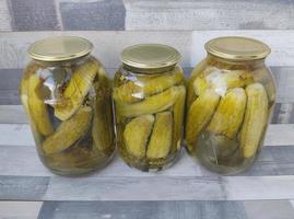 Pickled cucumbers in a glass jar. Three large jars of pickles on the table. Preparing food and snacks for the winter. photo