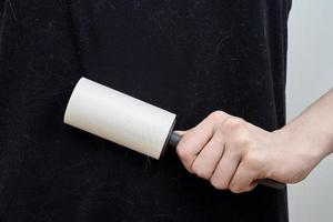 An unrecognizable woman cleans a black t-shirt with a clothes roller. photo