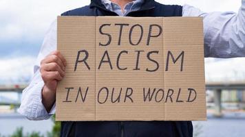Stop racism concept. Unrecognizable white person holds sign with text against racist. photo