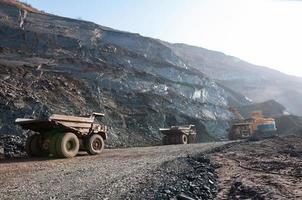 open cast mine dump trucks drive alone industrial area of iron ore quarry photo