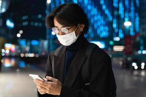 Portrait of an Asian businessman wearing a mask, in the street at night