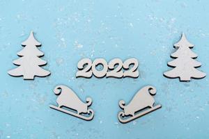 Merry Christmas and Happy New Year banner. Festive poster with a Christmas tree, sledges and snow on a blue background. New year 2022 with close up photo