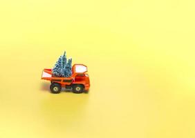 Yellow truck with Christmas trees on a beige background with lights. Holidays concept. Close up, with copy space. photo