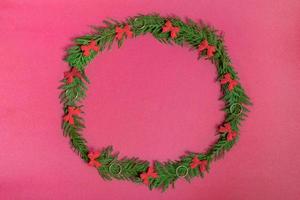 Christmas wreath of fir branches and decorations on a pink background. Flat lay, top view, copy space. festive composition photo