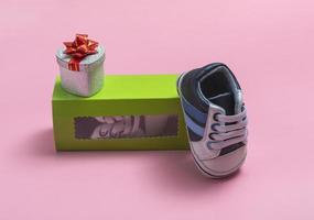 Mockup of children's shoes. Close up of a gift box and gumshoes for a newborn on a colored background. A gift to father photo