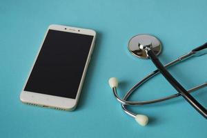 Medical concept stethoscope and mobile phone on a bright blue background. House call. Ambulance. With copy space. photo