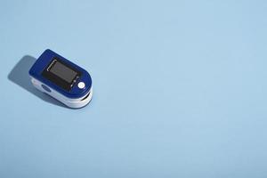 Portable pulse oximeter on a blue background with a hard shadow. Control of oxygen in the lungs. view from above photo