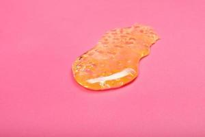 high thc, yellow cannabis wax resin marijuana concentrate on pink background macro photo