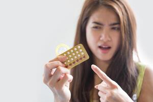 Young woman holding condom and contraceptive pills prevent pregnancy photo