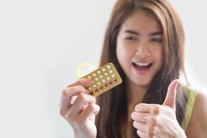 Young woman holding condom and contraceptive pills prevent pregnancy photo