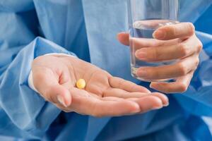 La mano de la mujer vierte las píldoras medicinales de la botella. foto