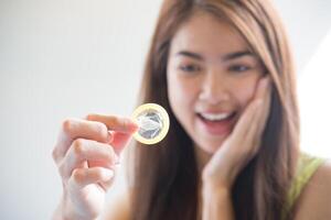 Young woman holding condom prevent pregnancy photo