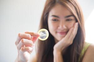 Young woman holding condom prevent pregnancy photo