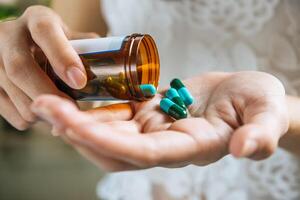 La mano de la mujer vierte las píldoras medicinales de la botella. foto