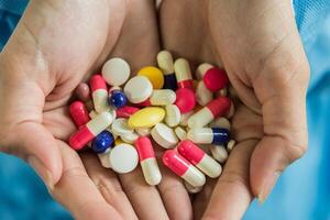 La mano de la mujer vierte las píldoras medicinales de la botella. foto