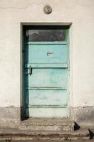 Ugly building with a turquoise color iron door. Aqua blue metal door. photo